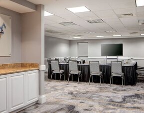 Meeting facility featuring a collaborative seating arrangement, presentation screen, and flexible event space at Houston Marriott South at Hobby Airport.