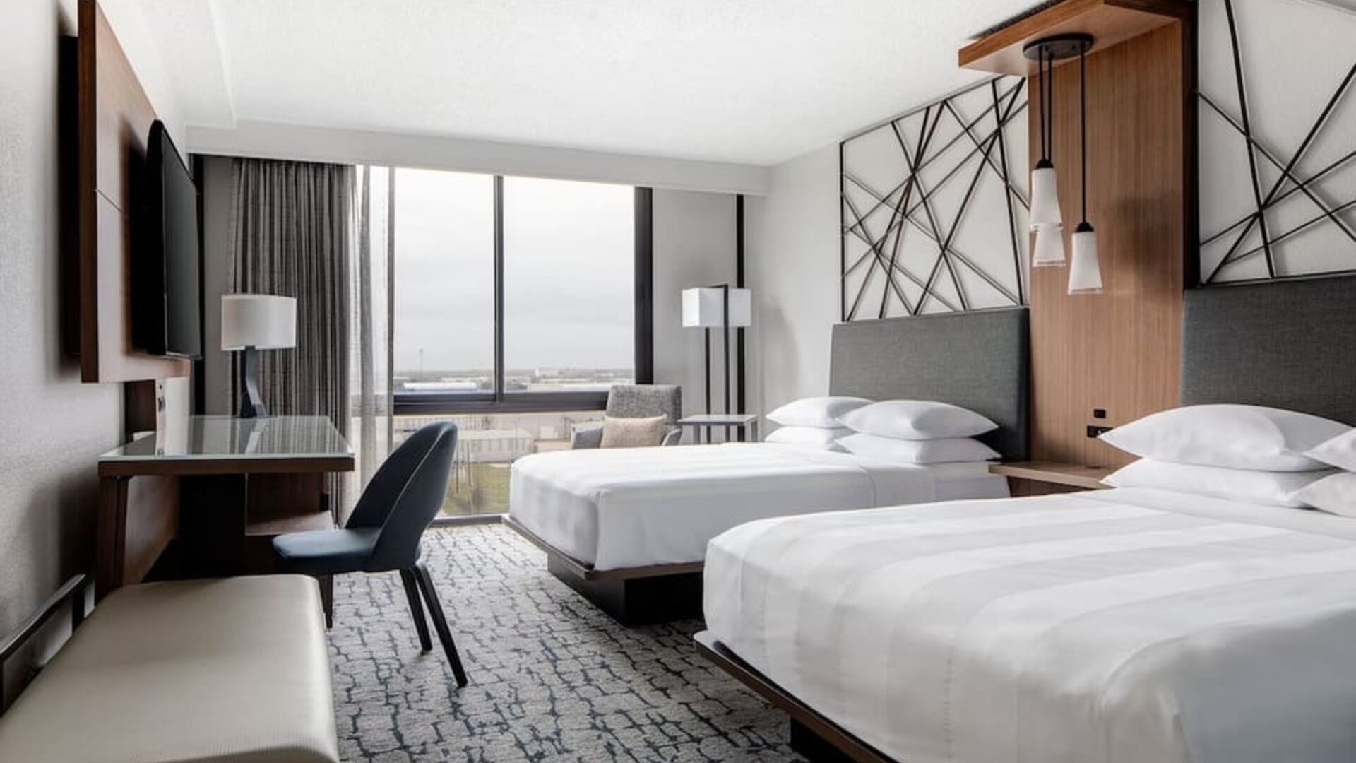Guest room featuring two beds, a spacious layout, large windows, and a dedicated work area at Houston Marriott South at Hobby Airport.
