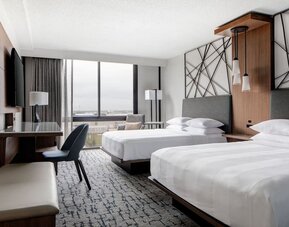 Guest room featuring two beds, a spacious layout, large windows, and a dedicated work area at Houston Marriott South at Hobby Airport.
