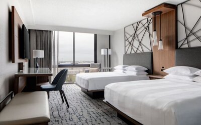 Guest room featuring two beds, a spacious layout, large windows, and a dedicated work area at Houston Marriott South at Hobby Airport.