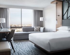 Guest room featuring a chaise lounge, city views, a workspace, and contemporary furnishings at Houston Marriott South at Hobby Airport.