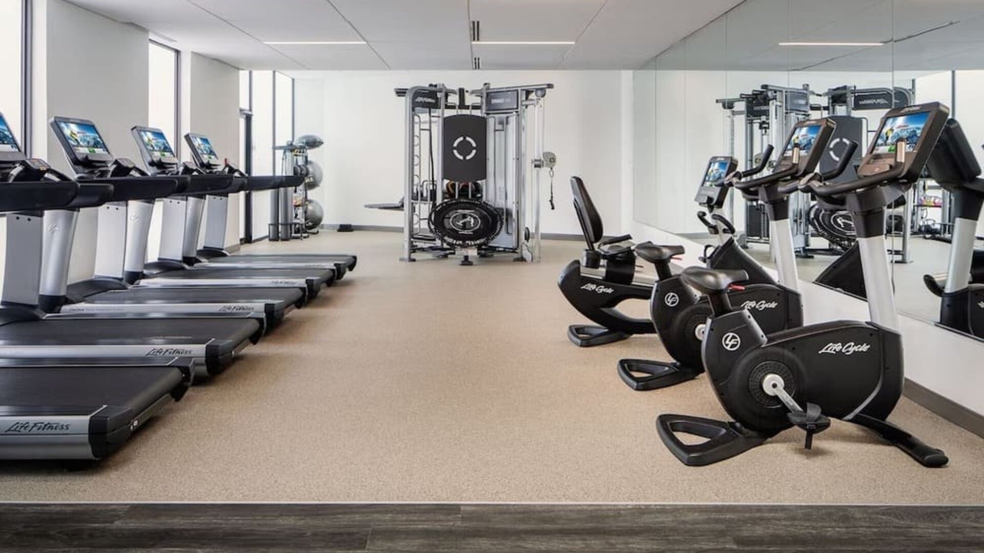 Fitness center featuring treadmills, stationary bicycles, strength-training equipment, and floor-to-ceiling mirrors at Houston Marriott South at Hobby Airport.