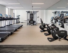 Fitness center featuring treadmills, stationary bicycles, strength-training equipment, and floor-to-ceiling mirrors at Houston Marriott South at Hobby Airport.