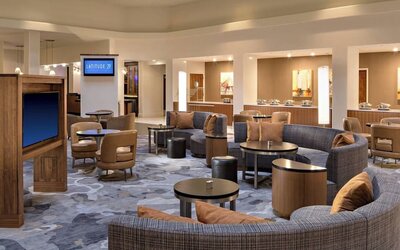 Lobby area featuring comfortable seating, gathering spaces, and access to dining amenities at Houston Marriott South at Hobby Airport.
