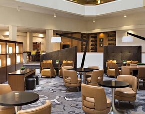 Lobby seating area featuring semi-private seating, communal tables, and contemporary décor at Houston Marriott South at Hobby Airport.