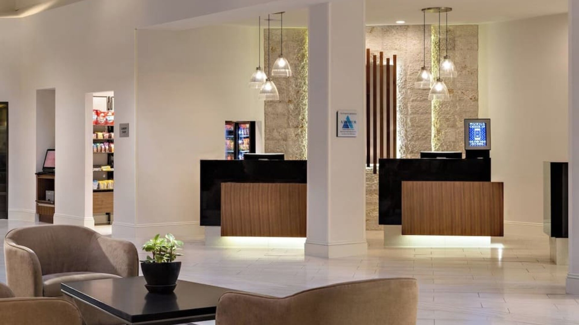 Reception area featuring illuminated check-in desks, modern lighting, and convenient access to hotel amenities at Houston Marriott South at Hobby Airport.