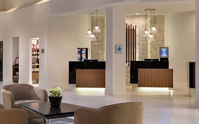 Reception area featuring illuminated check-in desks, modern lighting, and convenient access to hotel amenities at Houston Marriott South at Hobby Airport.