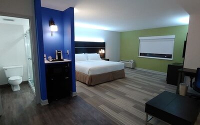 Spacious guest room featuring a king bed, a kitchenette area, a walk-in shower, and an open-concept layout at Holiday Inn Express Rolling Meadows-Schaumburg.