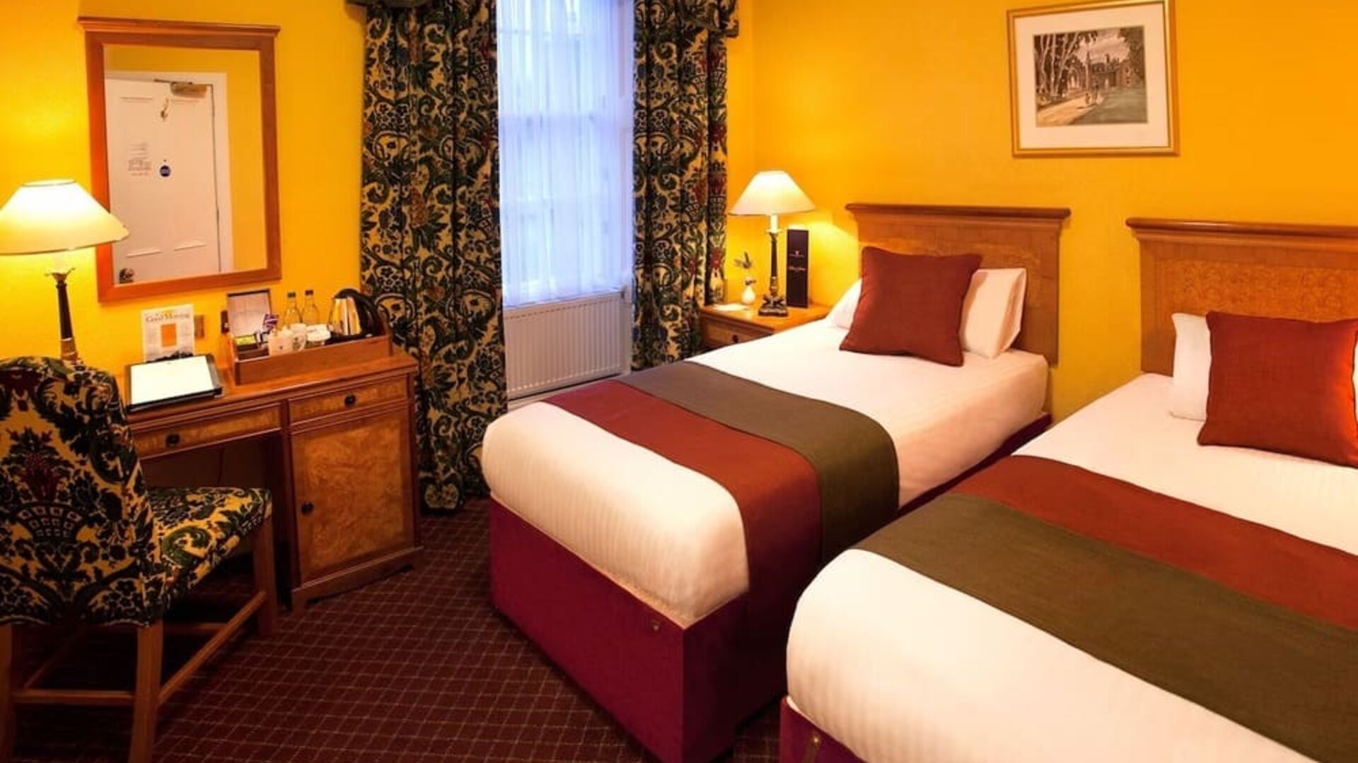 Guest room featuring two single beds, a writing desk, traditional décor, and warm-toned furnishings at The Royal Highland Hotel.