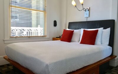 Guest room featuring a platform bed, oversized windows, accent pillows, and abundant natural light at The Mosser Hotel.
