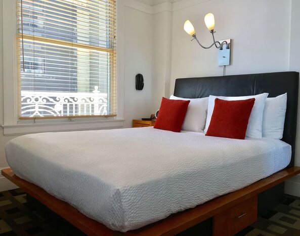 Guest room featuring a platform bed, oversized windows, accent pillows, and abundant natural light at The Mosser Hotel.