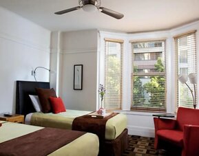 Guest room featuring two beds, a bay window, comfortable seating, and abundant natural light at The Mosser Hotel.
