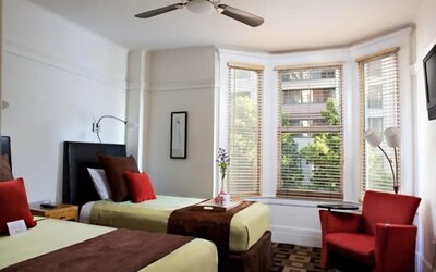 Guest room featuring two beds, a bay window, comfortable seating, and abundant natural light at The Mosser Hotel.