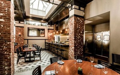 Dining area featuring an open kitchen, exposed brick accents, skylights, and contemporary seating at The Mosser Hotel.