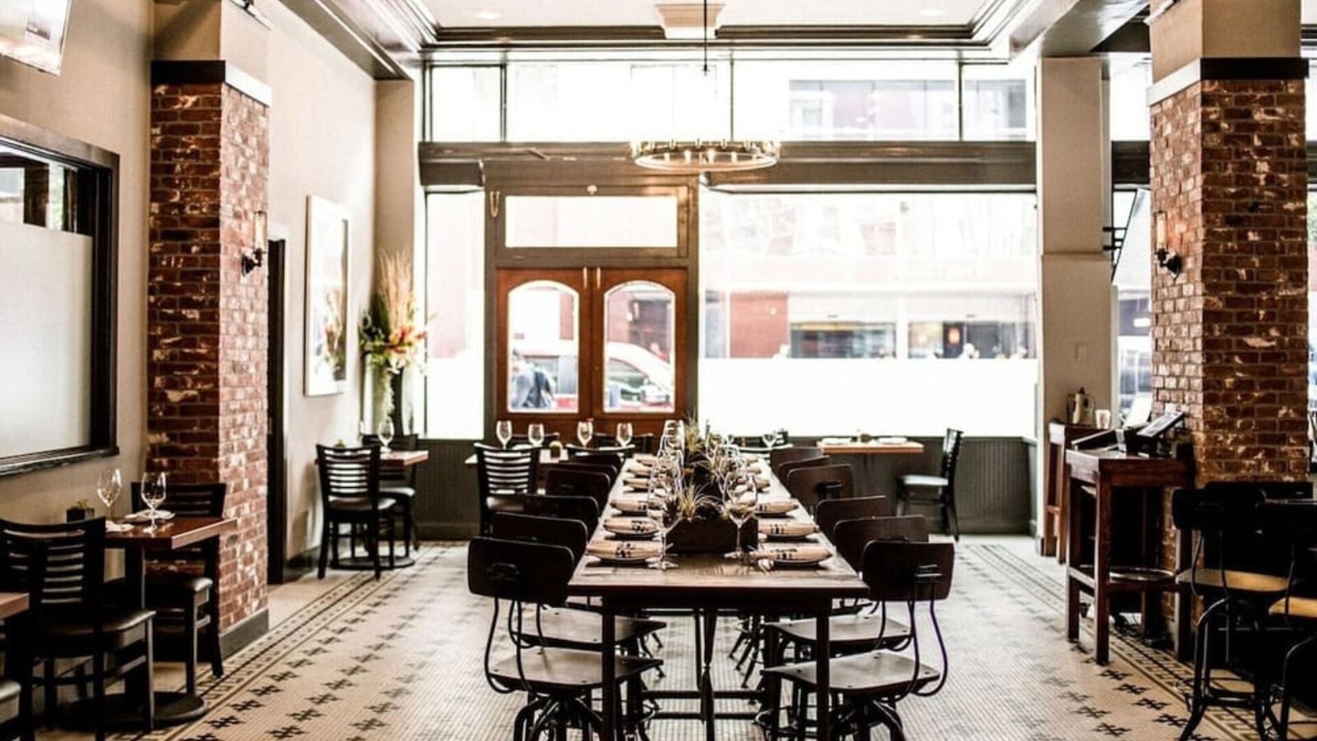 Restaurant featuring exposed brick walls, communal dining tables, high ceilings, and an industrial-inspired design at The Mosser Hotel.