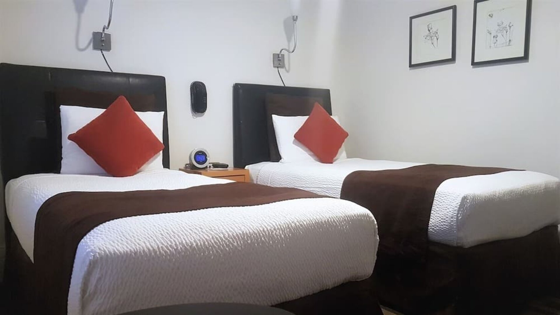 Guest room featuring two twin beds, minimalist décor, wall-mounted lighting, and modern furnishings at The Mosser Hotel.