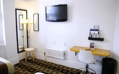 Guest room workspace featuring a wall-mounted television, a compact desk, modern seating, and a dedicated work area at The Mosser Hotel.
