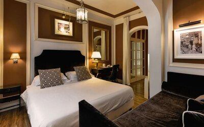 King room featuring a large bed, tall windows with sheer drapery, elegant lighting, and refined décor at Cellai Boutique Hotel.