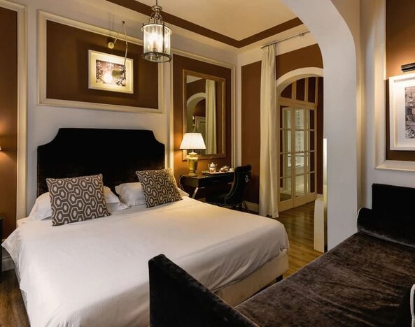 King room featuring a large bed, tall windows with sheer drapery, elegant lighting, and refined décor at Cellai Boutique Hotel.