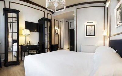 Spacious room featuring a large bed, decorative wall molding, mirrored wardrobes, and sophisticated furnishings at Cellai Boutique Hotel.
