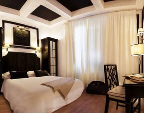 Spacious king room featuring coffered ceilings, a writing desk, contemporary lighting, and refined décor at Cellai Boutique Hotel.