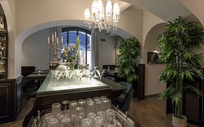 Bar area featuring crystal chandeliers, arched entryways, elegant glassware displays, and contemporary lounge seating at Cellai Boutique Hotel.