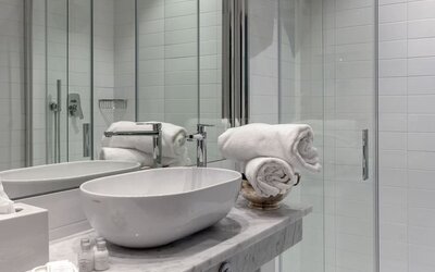 Bathroom featuring a marble vanity, vessel sink, glass-enclosed shower, and modern fixtures at Cellai Boutique Hotel.