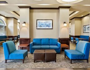 Hotel lobby seating area with blue upholstered furniture, accent lighting, and casual gathering spaces at Comfort Suites Frisco.