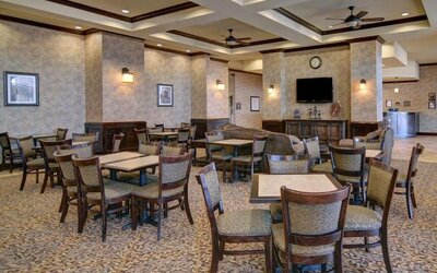 Spacious dining and lounge area with tables, upholstered seating, a television, and a fireplace at Comfort Suites Frisco.