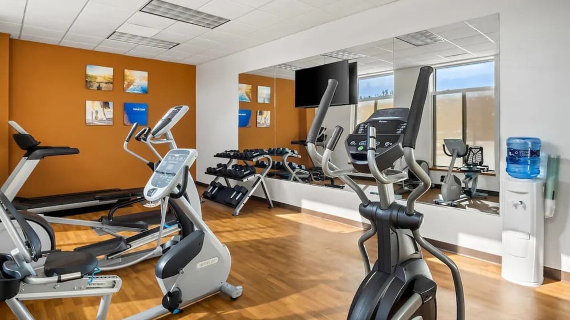 Hotel gym with treadmills, elliptical machines, dumbbells, and mirrored walls at Comfort Suites Frisco.