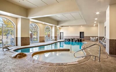 Alternate view of the indoor pool area highlighting the accessible lift, spa, and lounge seating at Comfort Suites Frisco.