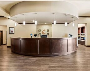 Reception desk with a curved granite counter, pendant lighting, and a convenient snack market at Comfort Suites Frisco.
