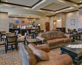 Breakfast and lounge area featuring comfortable leather seating, dining tables, and a self-serve breakfast station at Comfort Suites Frisco.