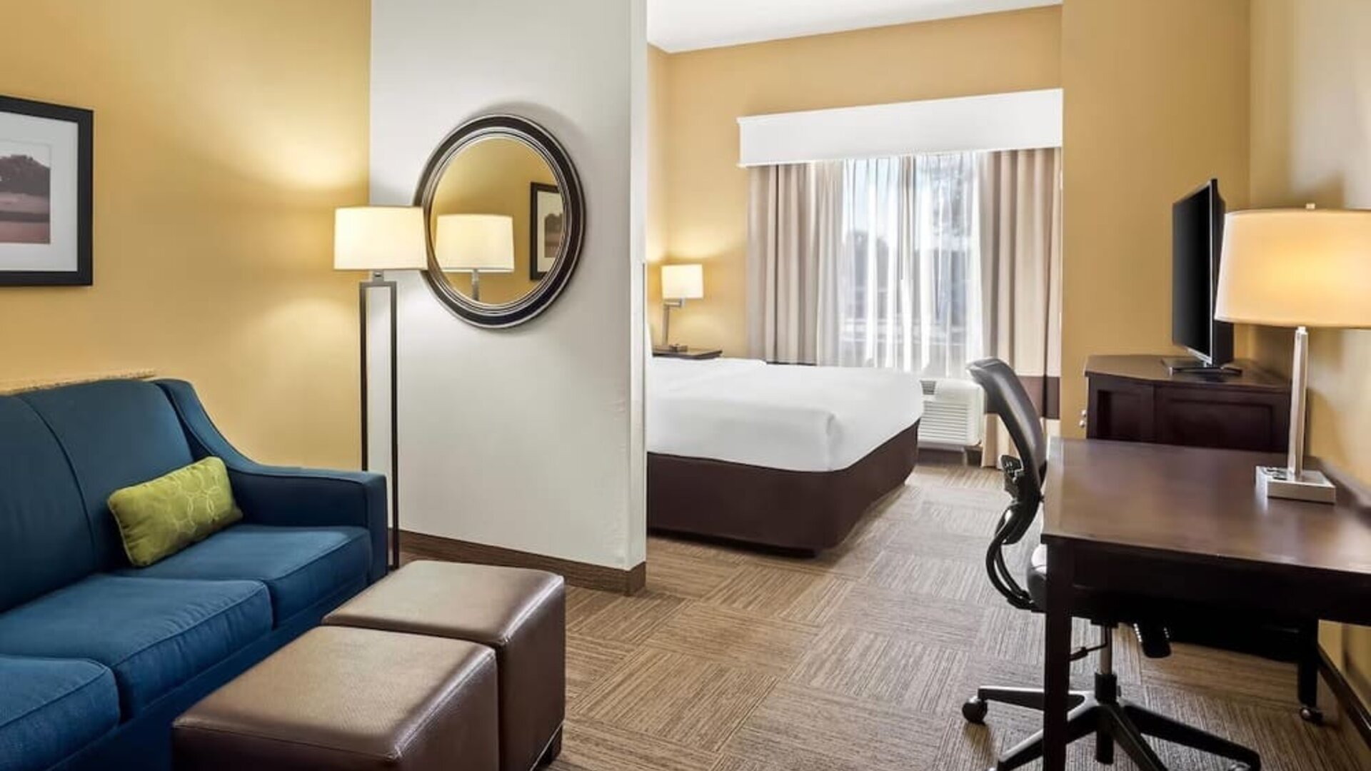 Guest suite with a separate living area, sofa, work desk, and king bedroom at Comfort Suites Frisco.