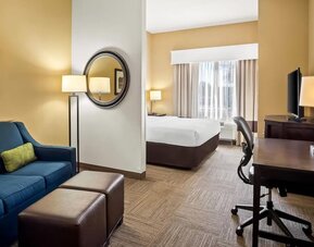 Guest suite with a separate living area, sofa, work desk, and king bedroom at Comfort Suites Frisco.