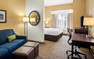 Guest suite with a separate living area, sofa, work desk, and king bedroom at Comfort Suites Frisco.