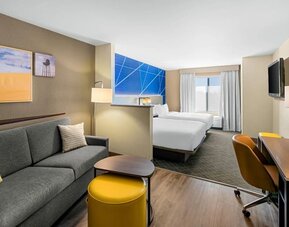 Spacious suite with two beds, a separate sitting area, sofa, workspace, and flat-screen television at Comfort Suites Vacaville-Napa Valley Area.
