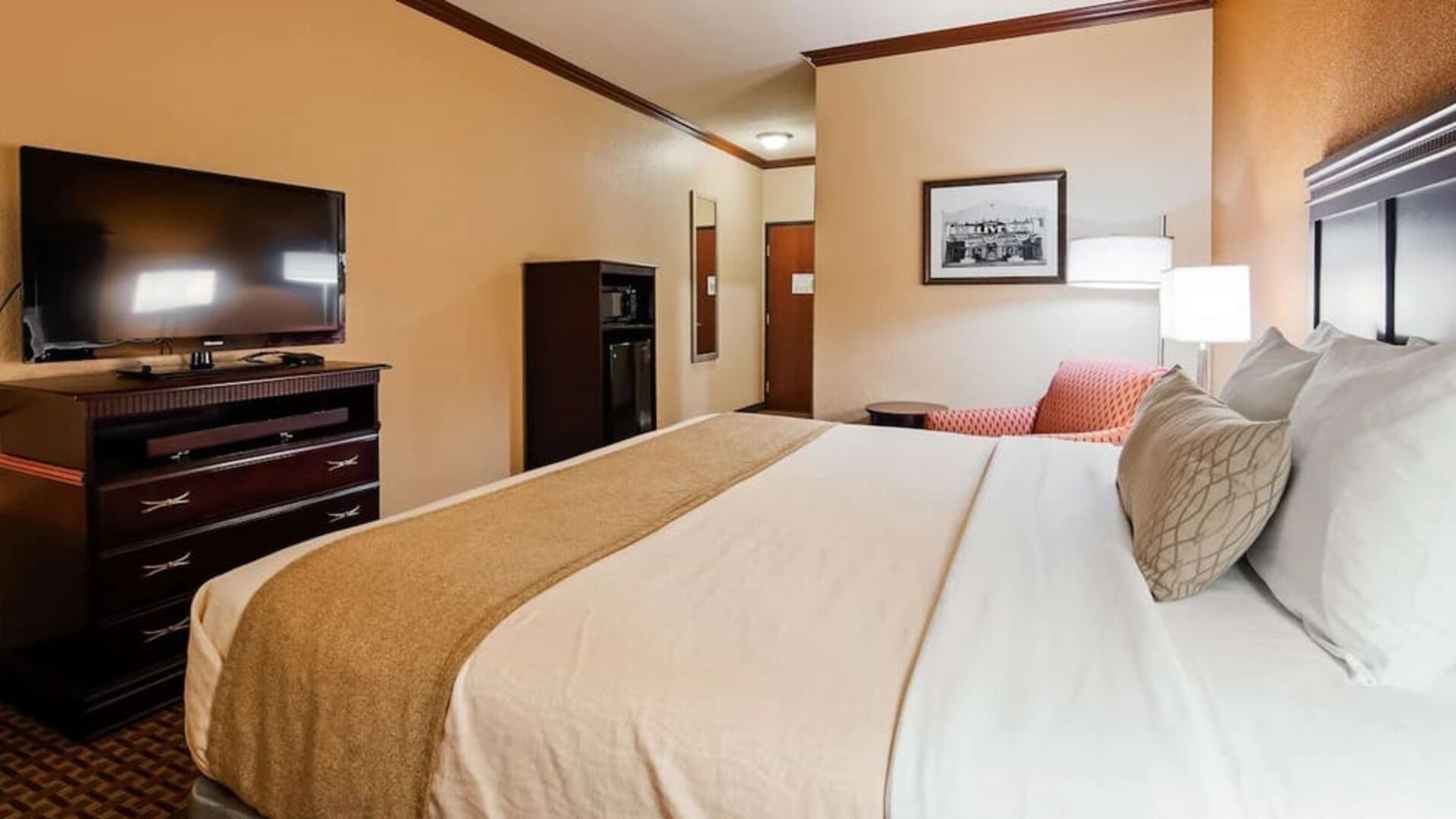 King guest room featuring a comfortable king bed, flat-screen television, microwave, mini refrigerator, and seating area at Best Western Granbury Inn & Suites.