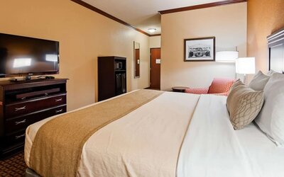 King guest room featuring a comfortable king bed, flat-screen television, microwave, mini refrigerator, and seating area at Best Western Granbury Inn & Suites.
