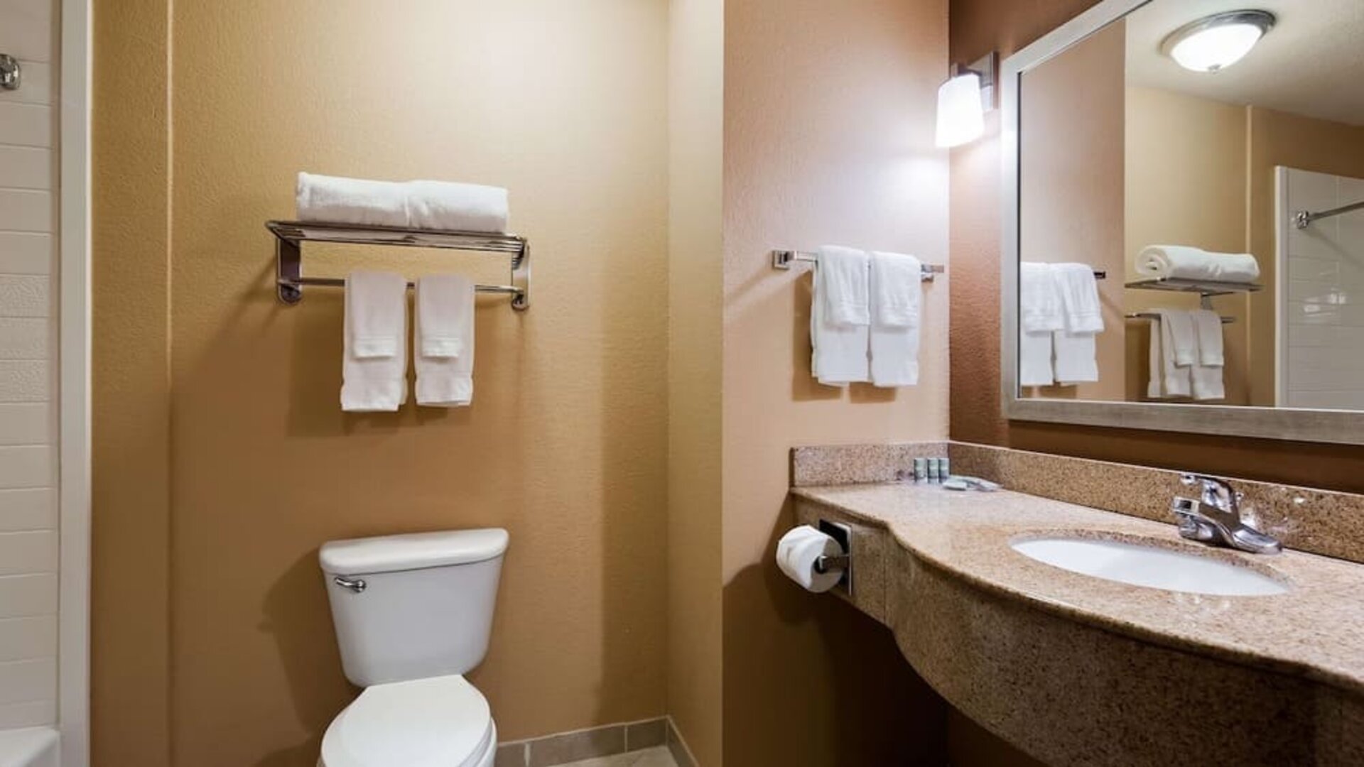Guest bathroom featuring a granite vanity, large mirror, fresh towels, and shower area at Best Western Granbury Inn & Suites.