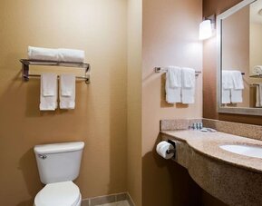 Guest bathroom featuring a granite vanity, large mirror, fresh towels, and shower area at Best Western Granbury Inn & Suites.