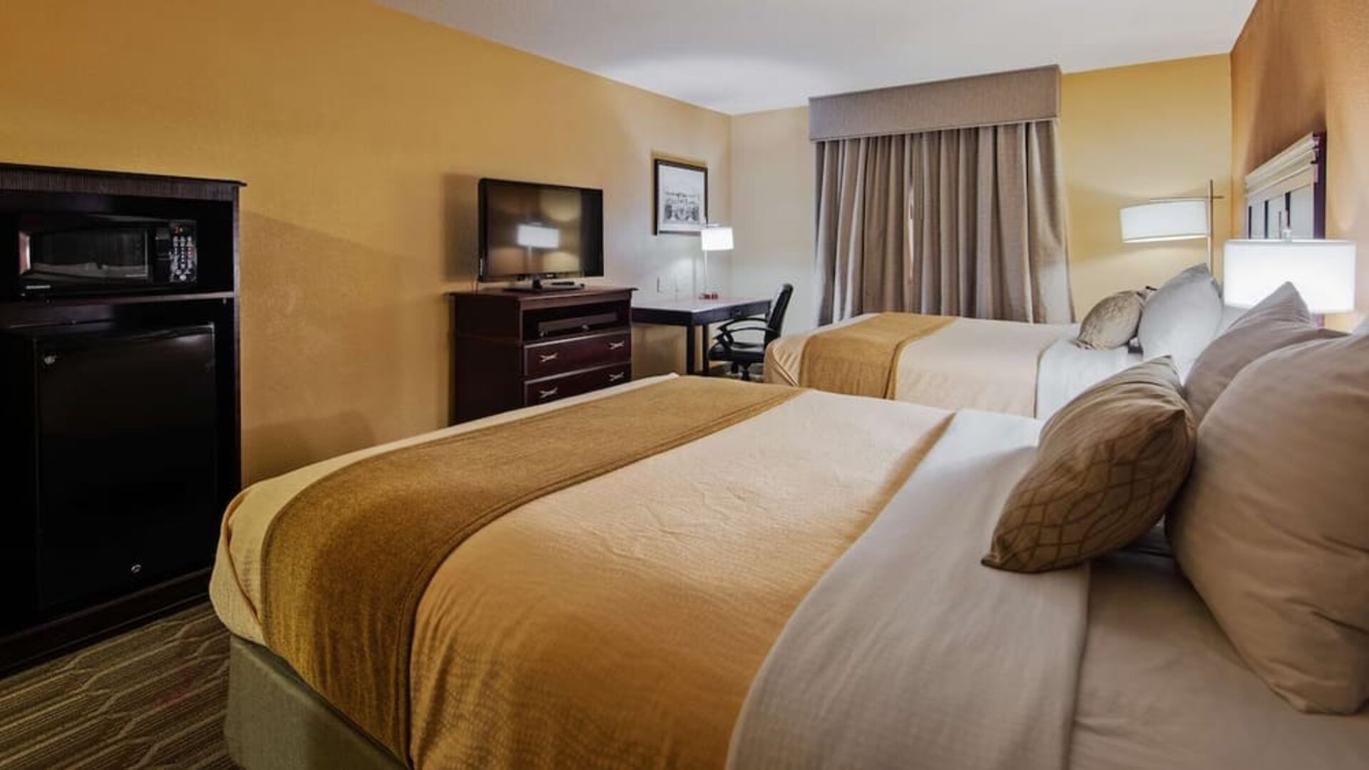 Guest room featuring two beds, flat-screen television, workspace, microwave, and mini refrigerator at Best Western Granbury Inn & Suites.