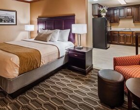 Spacious king guest room featuring a king bed, comfortable seating area, and kitchenette with refrigerator and cabinetry at Best Western Granbury Inn & Suites.