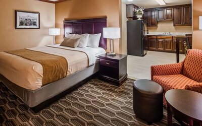 Spacious king guest room featuring a king bed, comfortable seating area, and kitchenette with refrigerator and cabinetry at Best Western Granbury Inn & Suites.
