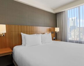 Bright king guest room featuring a king bed, bedside lighting, and a large window providing natural light at Hyatt Place San Jose Downtown.