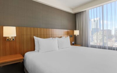 Bright king guest room featuring a king bed, bedside lighting, and a large window providing natural light at Hyatt Place San Jose Downtown.