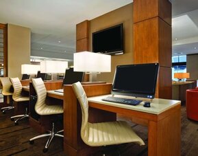 Business centre featuring multiple computer workstations, desk chairs, and individual task lighting at Hyatt Place San Jose Downtown.