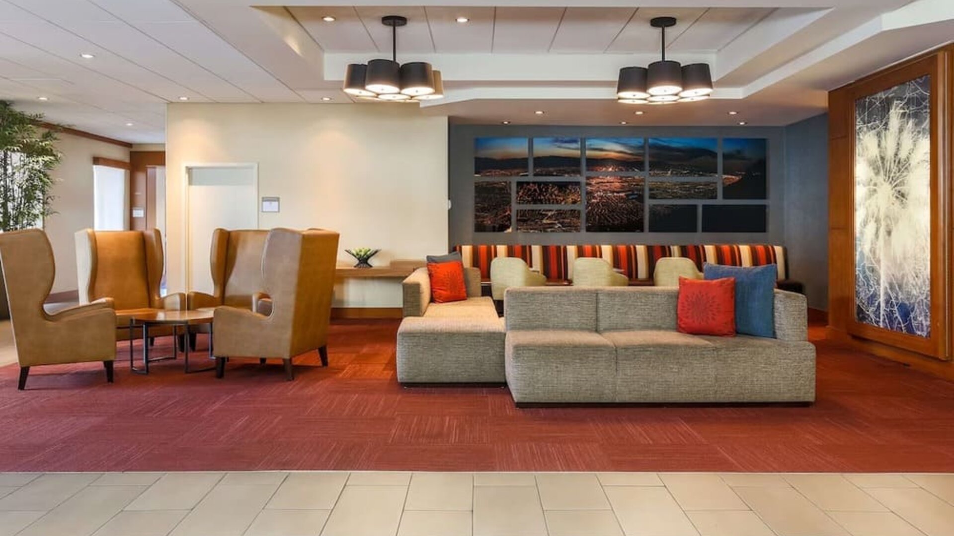 Contemporary hotel lobby featuring sofas, armchairs, colourful accent cushions, artwork, and multiple seating areas at Hyatt Place San Jose Downtown.