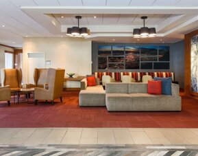 Contemporary hotel lobby featuring sofas, armchairs, colourful accent cushions, artwork, and multiple seating areas at Hyatt Place San Jose Downtown.