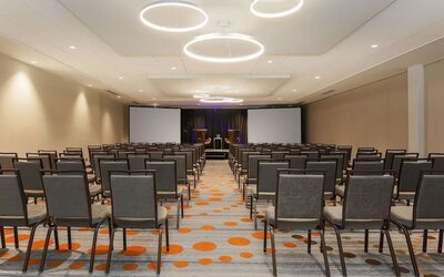 Spacious meeting facility arranged theatre-style with rows of chairs, presentation screens, and a stage area at Hyatt Place San Jose Downtown.